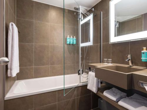 a bathroom with a tub and a sink and a shower at Novotel Brussels City Centre in Brussels