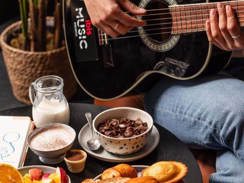 a person playing a guitar next to a bowl of food at Hotel ibis Lisboa Saldanha in Lisbon
