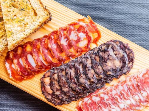 two types of meat on a cutting board with bread at Hotel ibis Lisboa Saldanha in Lisbon