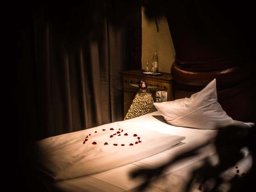a bed with some red rose petals on it at Mercure Hotel Riesa Dresden Elbland in Riesa