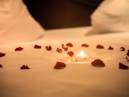 a lit candle sitting on top of a white sheet with a pile of petals at Mercure Hotel Riesa Dresden Elbland in Riesa