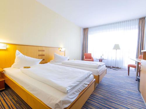 a hotel room with two beds and a window at Mercure Hotel Riesa Dresden Elbland in Riesa
