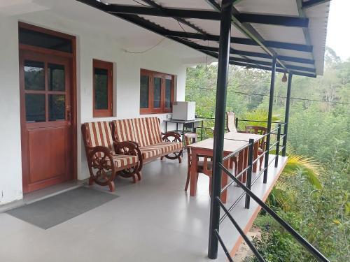 a porch with chairs and a table and a door at Ella Breeze Homestay in Ella