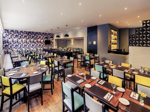 a restaurant with tables and chairs in a room at Mercure Sao Paulo JK in Sao Paulo