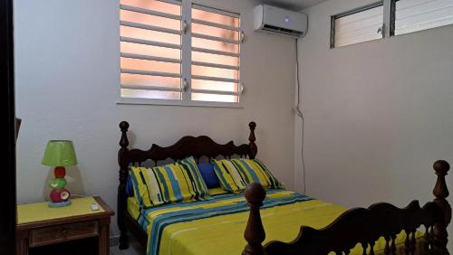 a bedroom with a bed with yellow sheets and a window at Appartement confortable à Le Lamentin, 70 m², jardin in Chambort