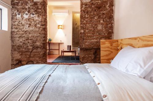 a bedroom with a bed with a brick wall at Casa Arrona Oaxaca in Oaxaca City