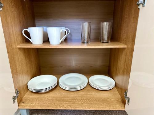 a wooden cabinet with plates and cups on it at Latitud Guesthouse Puerto Montt in Puerto Montt