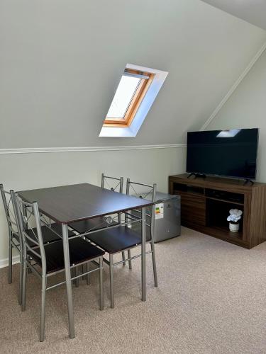 a dining room with a table and a tv and a window at Latitud Stays Puerto Montt in Puerto Montt