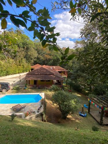 a house with a swimming pool in front of it at Chácara Recanto do Berzelai in Bueno Brandão