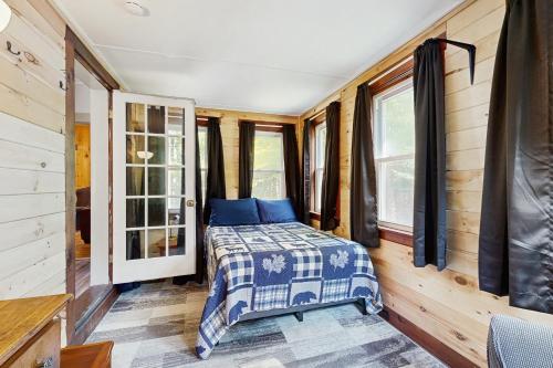 a bed in a room with wooden walls and windows at The Hollow in Jefferson