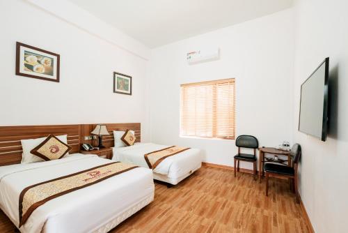 Una habitación de hotel con dos camas y un televisor. en Phoenix Mộc Châu Resort, en Mộc Châu