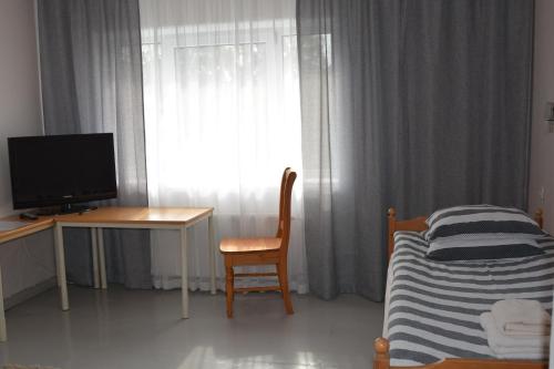 a bedroom with a bed and a desk and a television at K15HOSTEL guest apartments in Kobela