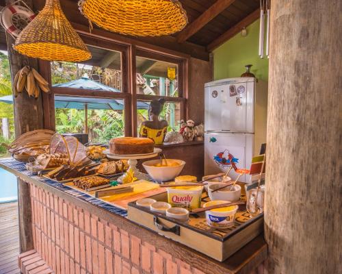 a kitchen with a counter with food and a refrigerator at Pousada Capitão Cook in Praia do Rosa