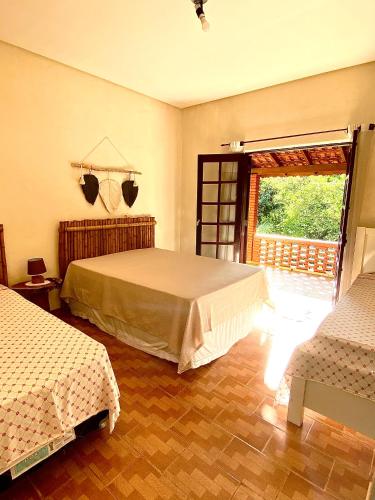 a bedroom with two beds and a large window at Chácara Recanto do Berzelai in Bueno Brandão