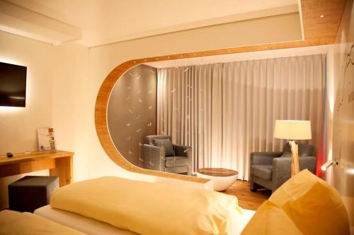 a bedroom with a bed and a chair and a mirror at Flair Hotel Nieder in Bestwig