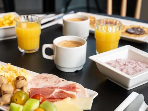 a table topped with plates of food and cups of coffee at ibis Genève Centre Gare in Geneva