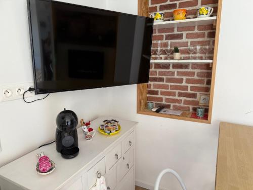 a flat screen tv on a wall above a dresser at La maisonnette confort de Tari et Nicolas in Juillan