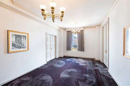an empty hallway with white walls and a chandelier at Hilton Milwaukee in Milwaukee