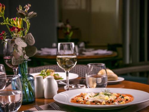 a table with a plate of food and glasses of wine at Sofitel Beirut Le Gabriel in Beirut