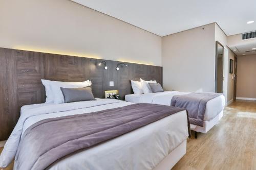 two beds in a hotel room with white walls at Transamerica Collection Goiania in Goiânia