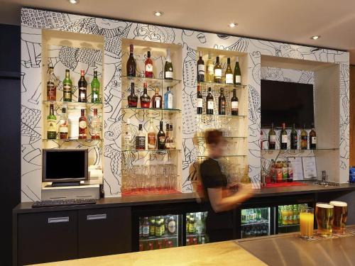 a man standing behind a bar with bottles of alcohol at ibis London Thurrock M25 in Grays Thurrock