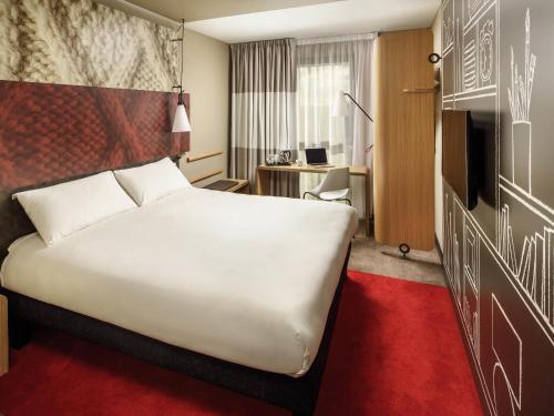 a hotel room with a large white bed and a desk at ibis London Docklands Canary Wharf in London