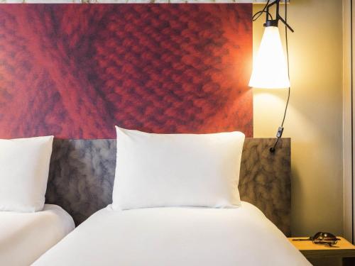a hotel room with two beds and a red wall at ibis London Docklands Canary Wharf in London