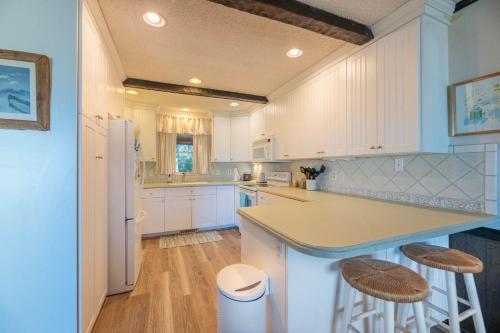 a kitchen with white cabinets and a counter and stools at The Green House in Kitty Hawk