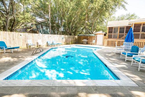 a swimming pool with blue chairs and a fence at The Green House in Kitty Hawk