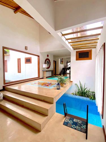 a living room with a swimming pool and stairs at Paraíso Casa Branca in Arraial d'Ajuda