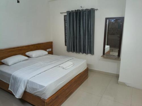 a bedroom with a bed and a window and a mirror at Tranquill Homestay in Tirupati