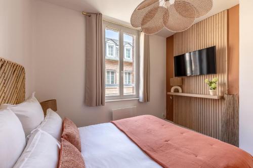 a bedroom with a bed with a television and a window at Pont'Au Rêve - Hypercentre - Venise Normande in Pont-Audemer