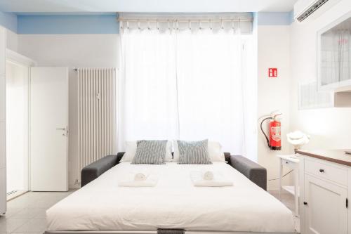 ein weißes Bett in einem Zimmer mit einem großen Fenster in der Unterkunft Casa Vespri apartments A & B in Mailand