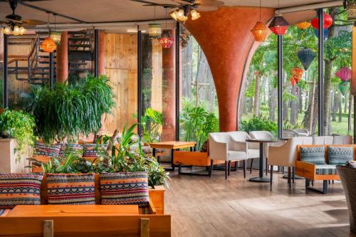 a restaurant with tables and chairs and plants at Phoenix Mộc Châu Resort in Mộc Châu