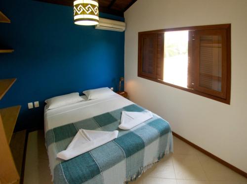 a bedroom with a bed with blue walls and a window at Manacá Flat in Itacaré