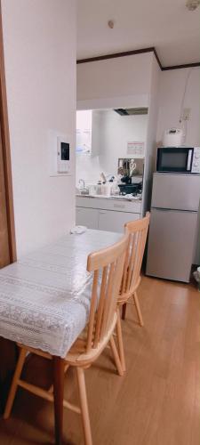 a kitchen with a table and two chairs and a refrigerator at Sea Bloom Hotel in Dejimamachi