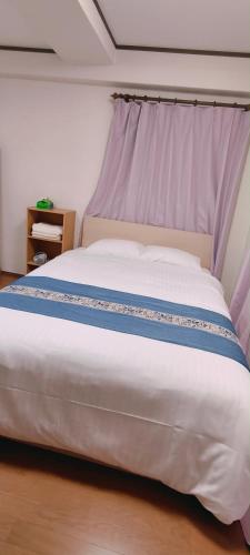 a large white bed with a purple head board at Sea Bloom Hotel in Dejimamachi