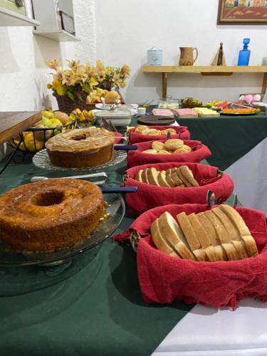 a table topped with cakes and pies on top at Pousada Linda Borboleta in Conservatória