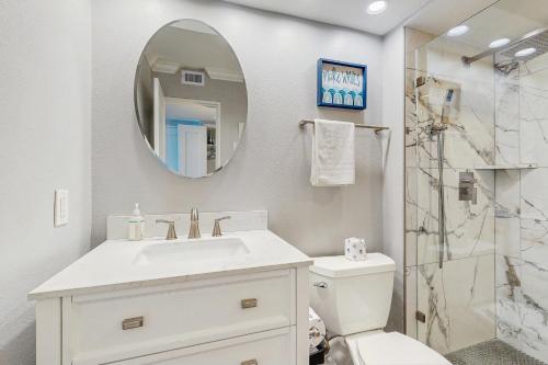 Un baño blanco con lavabo y espejo. en Sunset Dream, en Galveston