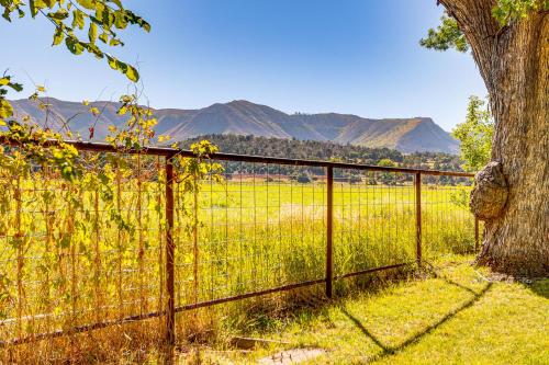 a fence with a tree and mountains in the background at Patio and Mountain Views Farmhouse in Mancos! in Mancos