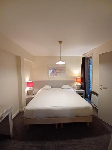 a bedroom with a white bed and two lamps at Koffieboontje Budget in Bruges