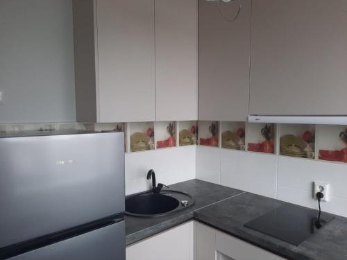 een witte keuken met een wastafel en een koelkast bij Studio Apartment 2 in Rēzekne