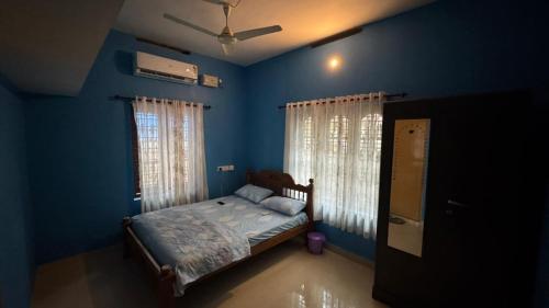 a blue bedroom with a bed and a window at Souparnika in Varkala