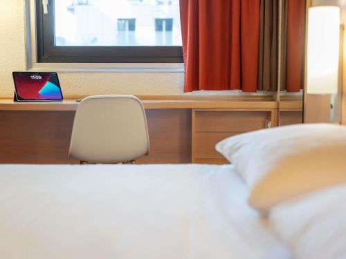 a bedroom with a bed and a desk with a window at ibis Paris 17 Clichy-Batignolles in Paris
