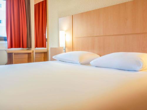 a bedroom with a white bed with two pillows at ibis Paris 17 Clichy-Batignolles in Paris