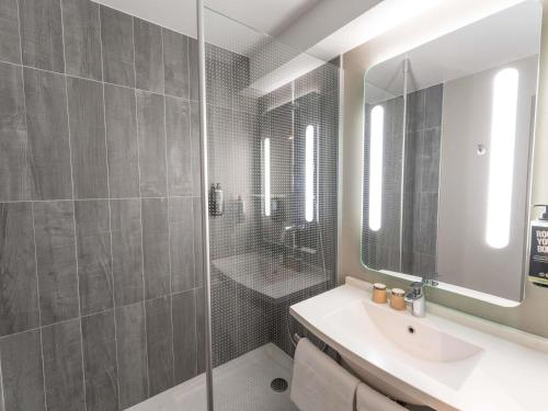 a bathroom with a sink and a shower with a mirror at ibis Paris 17 Clichy-Batignolles in Paris