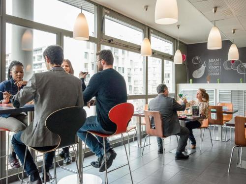 a group of people sitting at tables in a restaurant at ibis Paris 17 Clichy-Batignolles in Paris