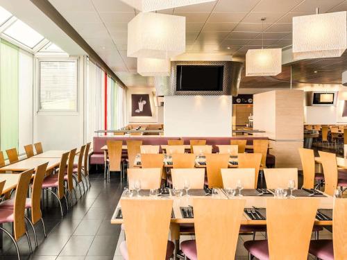 a restaurant with tables and chairs and a tv at ibis Paris 17 Clichy-Batignolles in Paris