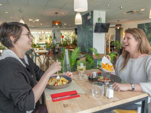 two women sitting at a table with a bowl of food at ibis Paris 17 Clichy-Batignolles in Paris