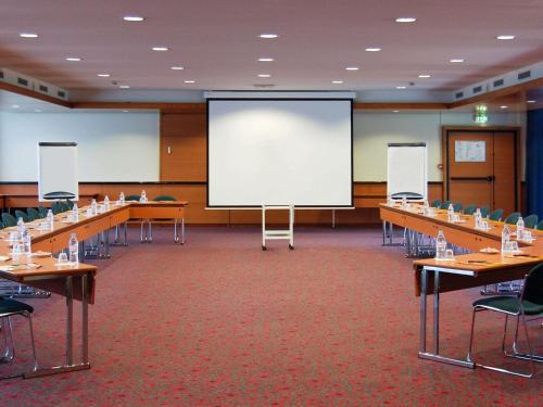 a conference room with tables and a large screen at ibis Paris 17 Clichy-Batignolles in Paris